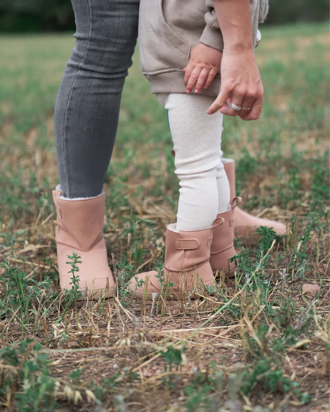 Lifestyle fotografija barefoot cizama Siberia roze dete stoji na travi pored odrasle osobe