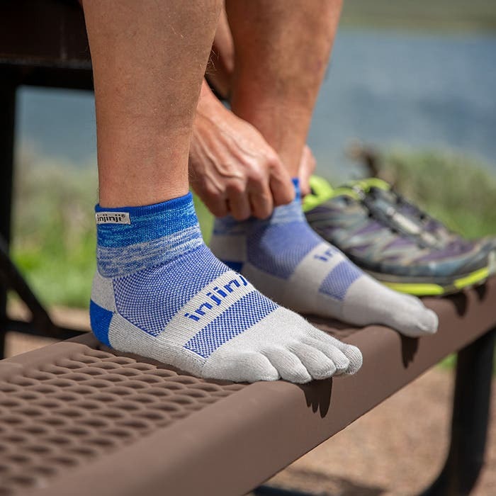 Detalj stopala u Injinji Trail Midweight Mini-Crew Neptune carapama na klupi