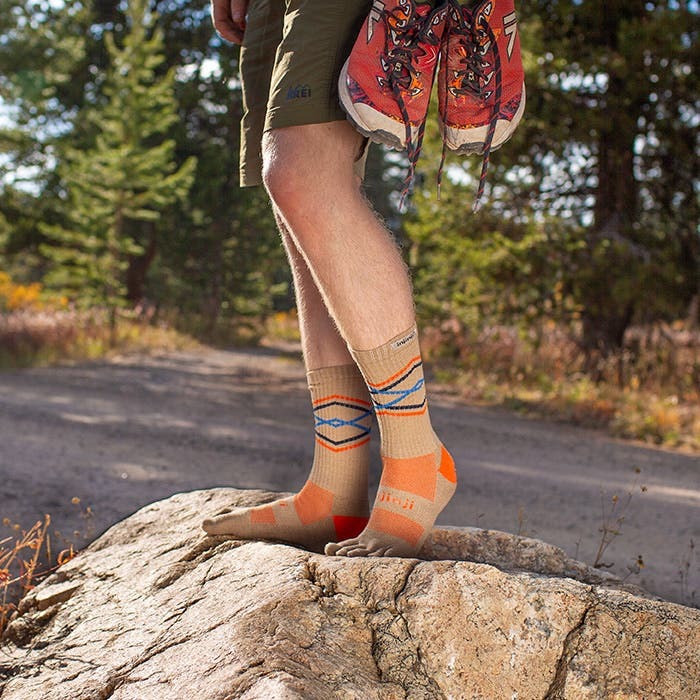 Model stoji na steni u Injinji Trail Midweight Crew Grain carapama