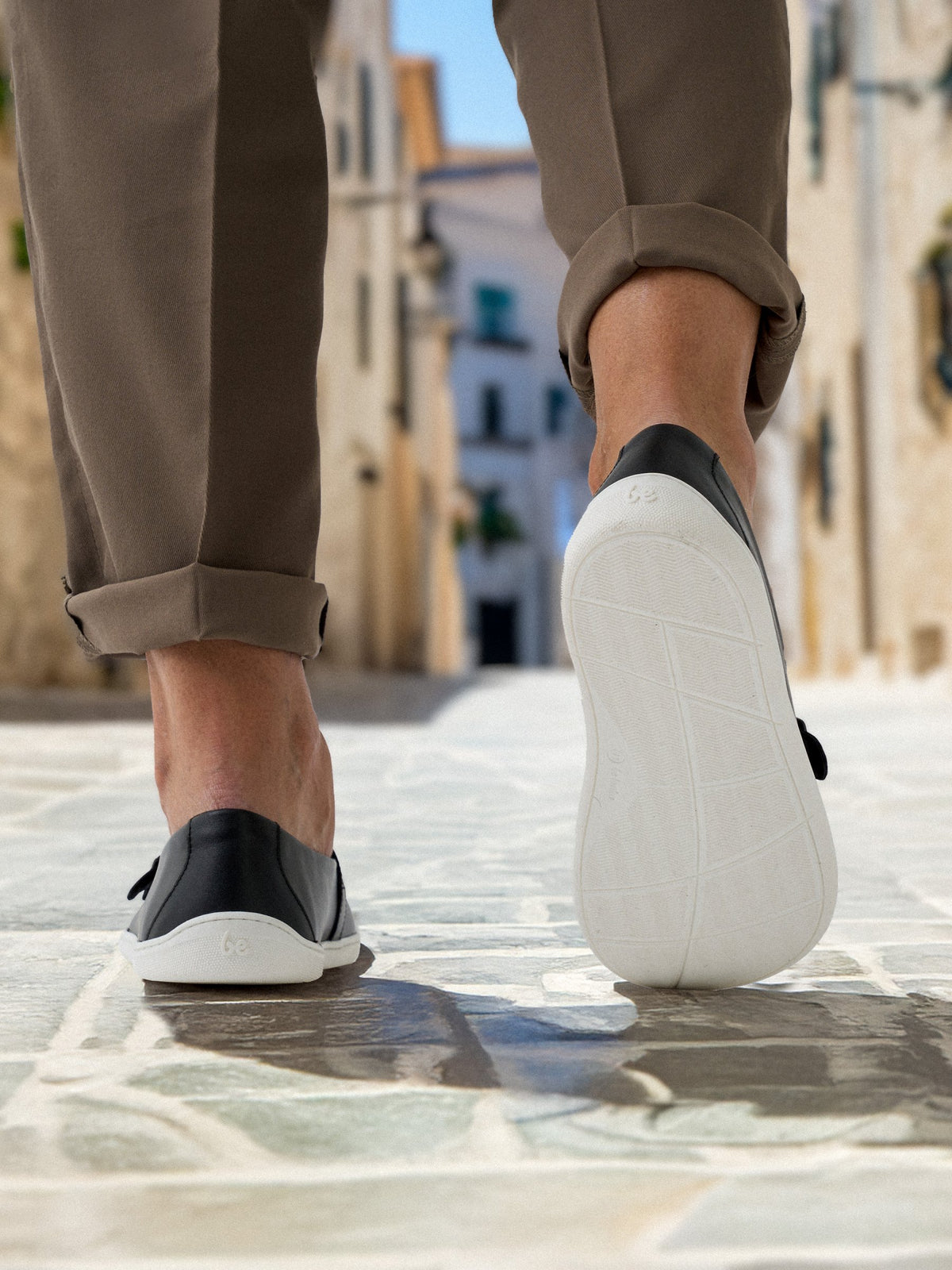 Zadnji prikaz crno-belih barefoot mokasina Be Lenka Amadeus u hodu – fokus na djon i peta desne patike