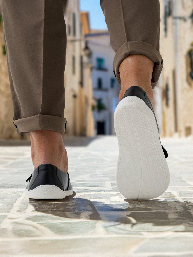 Zadnji prikaz crno-belih barefoot mokasina Be Lenka Amadeus u hodu – fokus na djon i peta desne patike