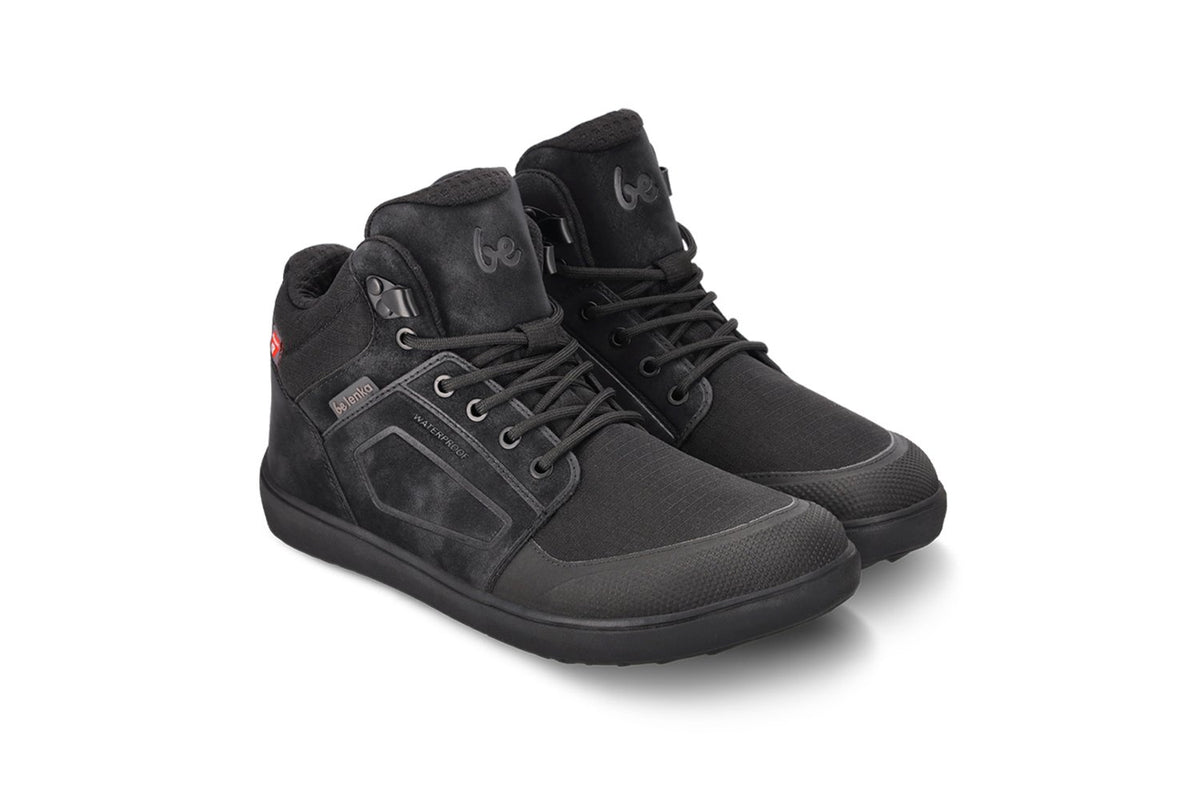 Arctic Edge All Black barefoot čizme par položen pod blagim uglom na beloj pozadini