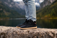 Arctic Edge crne barefoot čizme na nozi pogled sa strane na kamenu
