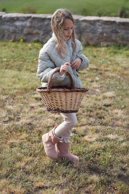 Lifestyle fotografija barefoot cizama Siberia roze dete stoji na travi sa korpom